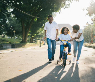 Parents teacher their daughter how to ride a bicycle